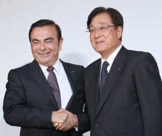 記者会見で握手する日産自動車のカルロス・ゴーン社長(左)と三菱自動車の益子修会長(5月12日、横浜市神奈川区)