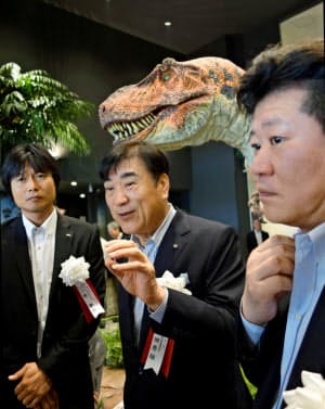 8月1日、第3の「変なホテル」が愛知県蒲郡市で開業した。フロントの恐竜の前で記者らと話すHISの沢田氏（中央）