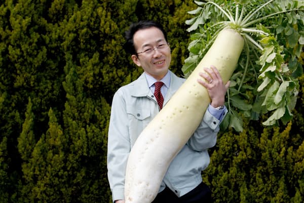 「万田酵素」を使って栽培したジャンボ大根を担ぐ万田発酵の松浦良紀社長