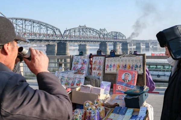 丹東の中朝友誼橋付近にある土産物店で品物を物色する男性。この橋は朝鮮戦争中に米軍の爆撃を受けた後、再建されたものだが、壊れた橋の一部は現在、戦争記念碑になっている（PHOTOGRAPH BY ELIJAH HURWITZ）
