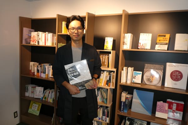 一見、お互いに無関係の本が並ぶ書棚の前で展示方法を解説する伊藤晃氏